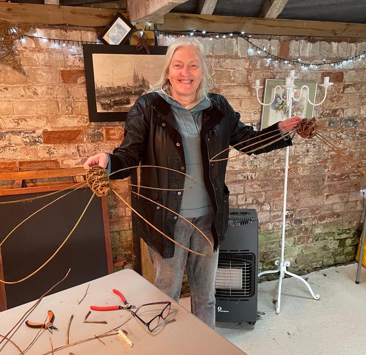 Deborah Cooke in her studio holding willow dragonfly sculptures