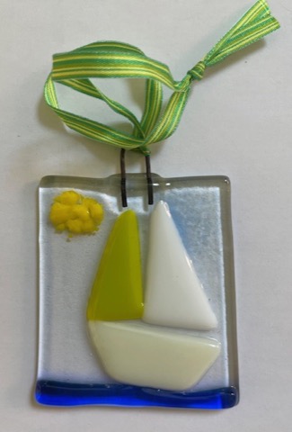 Fused glass sailboat ornament with green and white sails on a ribbon