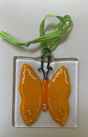 Orange fused glass butterfly ornament on a striped ribbon