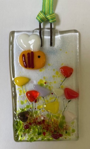 Fused glass panel with bee hovering over colourful flowers