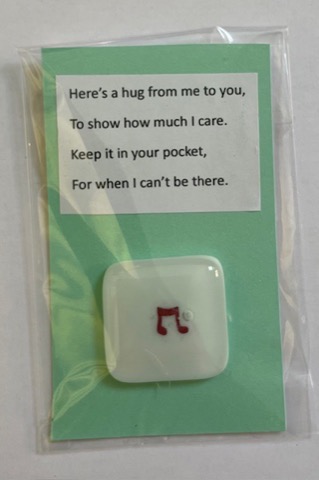 White fused glass pocket hug with red musical note on a gift card